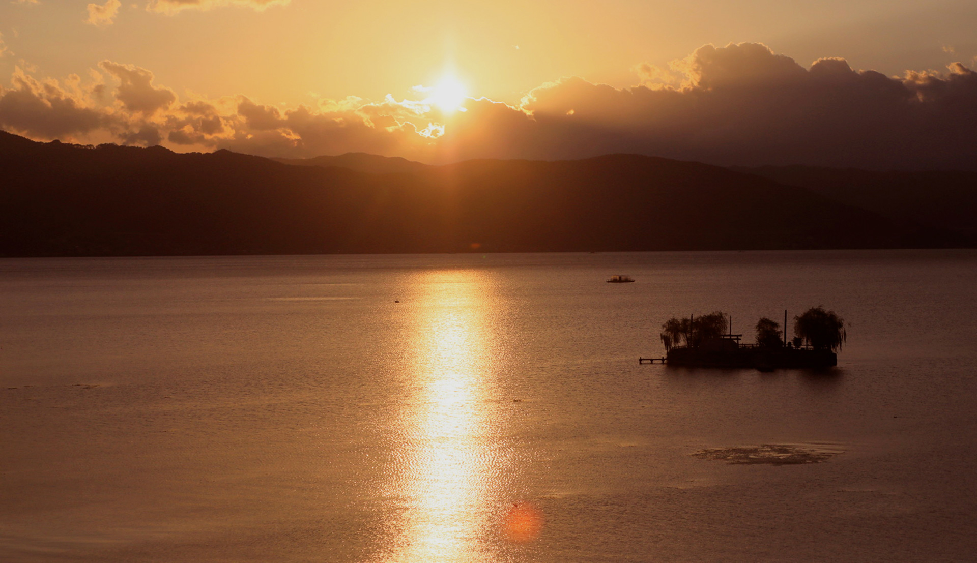 夕日が湖面に反射し、穏やかな時間が流れる湖の風景